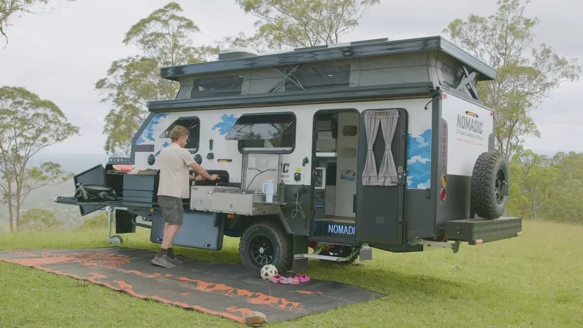 Family cooking at the external kitchen of a Nomadic pop-top